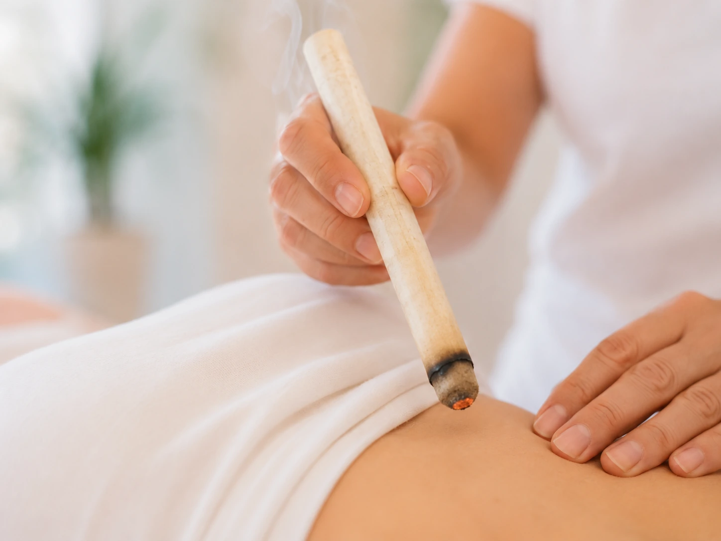 Glimmender Moxa-Kegel über einem Punkt am Rücken einer Patientin im Akupunktur Zentrum Oberengstringen
